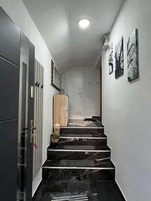 a hallway with black tile floors and white walls at Stan na dan Apartman Durakovic in Cazin