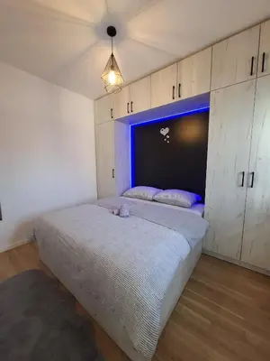a bedroom with a large bed with a blue headboard at Apartman Sweet in Prijedor
