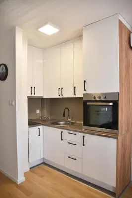 a kitchen with white cabinets and a sink and a microwave at Apartman Sweet in Prijedor