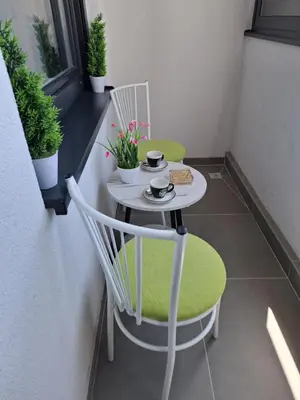 a small table and chairs on a balcony with plants at Apartman Sweet in Prijedor