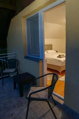 a room with a chair and a bedroom with a bed at Vikendica Sara in Šipovo