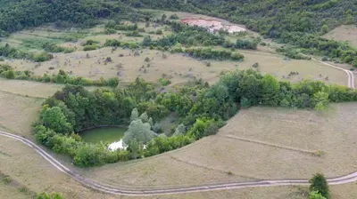 an aerial view of a field with a pond and a road at Vikendica Sara in Šipovo