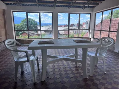 a table and chairs in a room with windows at Casa SOLE in Bihać