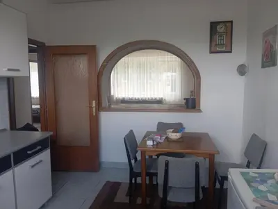 a kitchen with a table with chairs and an arch window at MAM apartmani in Bosanski Brod