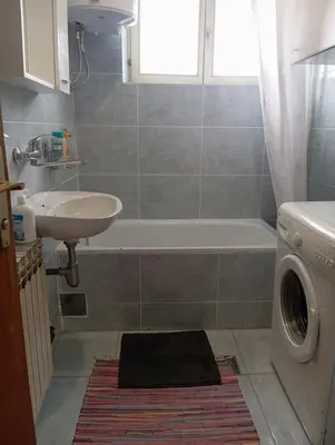 a bathroom with a sink and a washing machine at MAM apartmani in Bosanski Brod