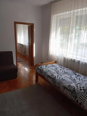 a bedroom with a bed and a window and a chair at MAM apartmani in Bosanski Brod