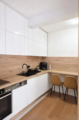 a kitchen with white cabinets and a sink and two chairs at Lana Apartmani Autor in Tuzla
