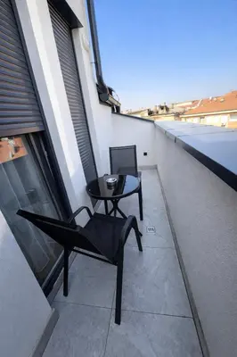 a balcony with a table and a chair on a building at Lana Apartmani Autor in Tuzla