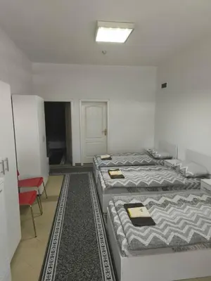 a room with three beds and a red chair at Vila Gunša in Šipovo