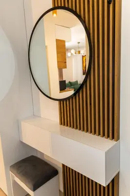 a mirror on a wall above a white shelf with a stool at Urban Studio II
