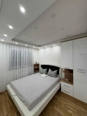 a white bedroom with a large bed and a white cabinet at Apartman Andjela Doboj in Doboj