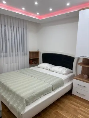 a bedroom with a large white bed with a pink lighting at Apartman Andjela Doboj in Doboj
