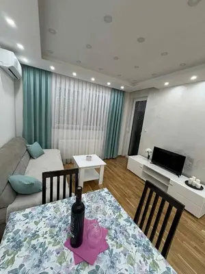 a living room with a table with a bottle of wine on it at Apartman Andjela Doboj in Doboj