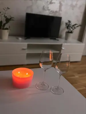 two wine glasses and a candle on a table at Apartman Andjela Doboj in Doboj