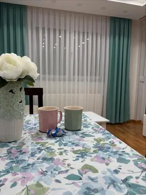 a table with two cups and a vase of flowers at Apartman Andjela Doboj in Doboj