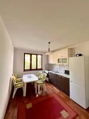 a kitchen with a table and a white refrigerator at Apartman Hela in Ivišovo Greblje
