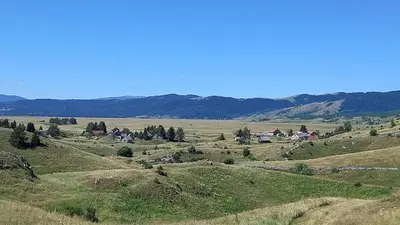 a large open field with houses on a hill at Planinska Vikendica Kupres Novo Selo