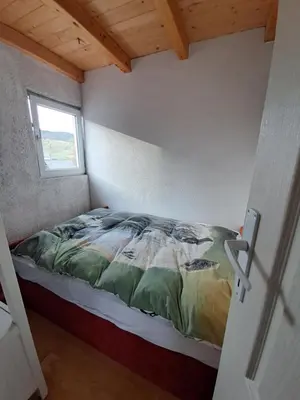 a bed in a small room with a window at Planinska Vikendica Kupres Novo Selo