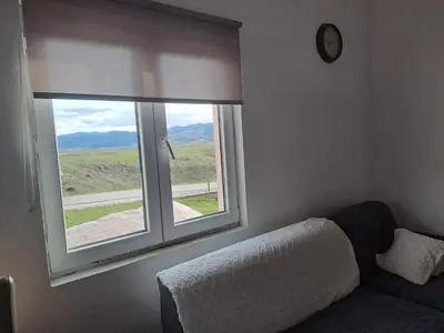 a room with a window with a couch and a clock at Planinska Vikendica Kupres Novo Selo