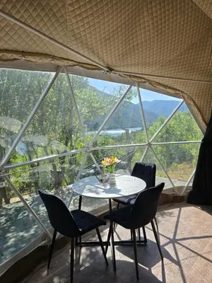 a table and chairs in front of a large window at Kamp Glamp Plivska Oaza in Jajce