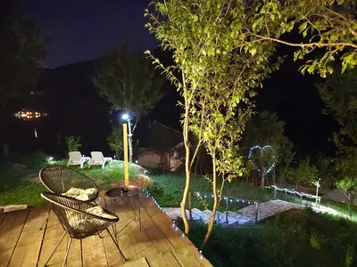 a table and chairs on a wooden deck at night at Kamp Glamp Plivska Oaza in Jajce
