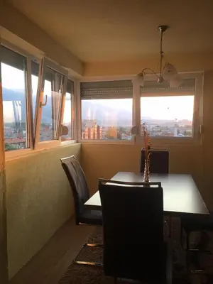 a dining room with a table and chairs and windows at ZiiNa Skyline Apartment in Bihać