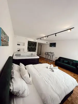 a large white bed in a room with a tub at RajRaj apartmani Gradiska in Bosanska Gradiška