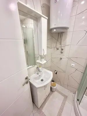 a white bathroom with a sink and a mirror at Apartment M&S in Bosanski Novi