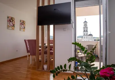 a living room with a television and a dining room table at Apartman Milica in Doboj