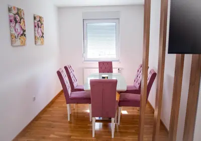 a dining room with a table and chairs and a window at Apartman Milica in Doboj