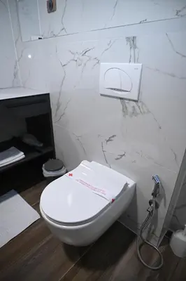 a white toilet in a bathroom with a marble wall at Hotel LOBBY PLUS in Bihać
