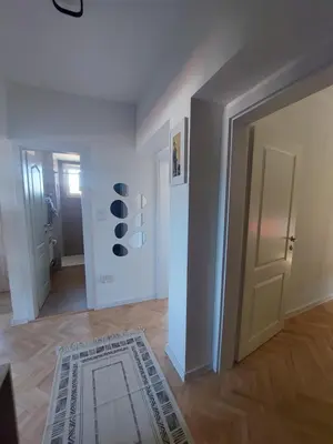 a room with a hallway with a door and a rug at City Vibe Apartment in Tuzla