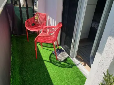 two red chairs on a porch with green grass at City Vibe Apartment in Tuzla
