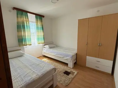 a bedroom with two beds and a cabinet and a rug at Dream house in Laktaši