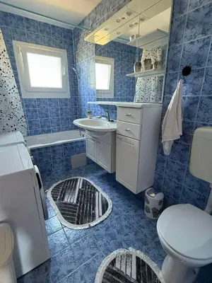 a blue tiled bathroom with a sink and a toilet at Dream house in Laktaši