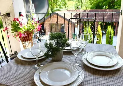 a table with plates and wine glasses on a balcony at Apartman M&B - Kuća za odmor-Karanovac in Topići
