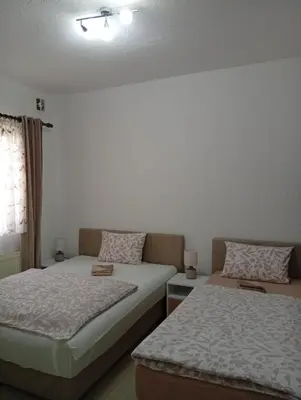 a bedroom with two beds and a window at Apartman EM-Bajkeraj in Bihać