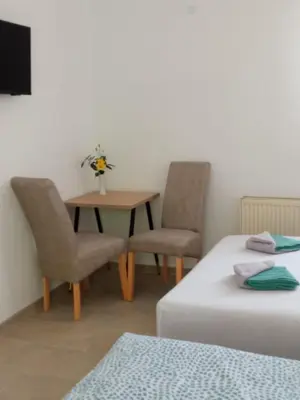 a room with two beds and a table and chairs at Apartman EM-Bajkeraj in Bihać