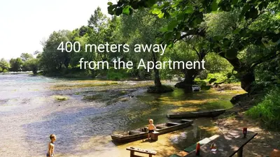 a river with two people in boats in the water at Apartman EM-Bajkeraj in Bihać