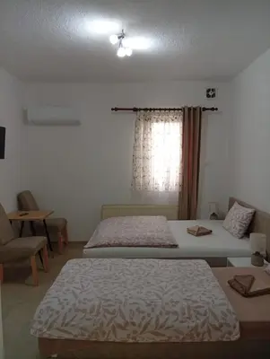 a bedroom with two beds and a window at Apartman EM-Bajkeraj in Bihać