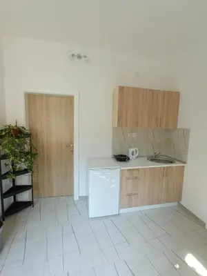 a kitchen with wooden cabinets and a white tile floor at Apartman EM-Bajkeraj in Bihać
