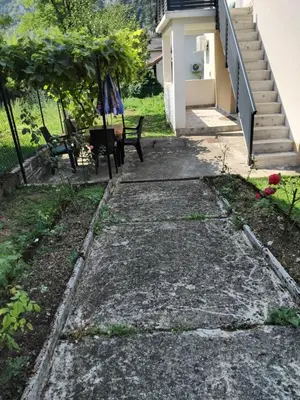 a concrete walkway leading to a house with two benches at Dinn in Jajce