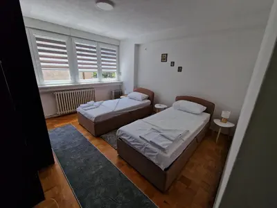 a bedroom with two beds and a window at MI apartman in Tuzla