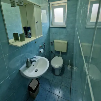 a bathroom with a sink and a toilet and a mirror at MI apartman in Tuzla
