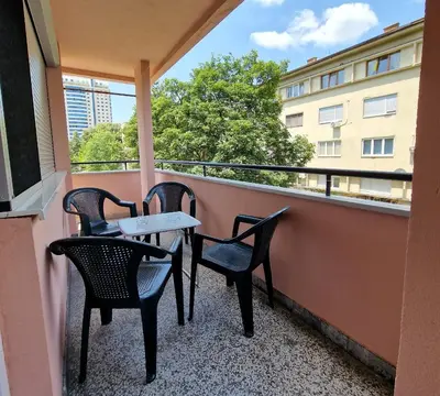 a balcony with three chairs and a table on a building at MI apartman in Tuzla