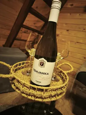 a bottle of wine in a basket with two glasses at Janjske Otoke Brvnara Tiho Ognjiste in Šipovo