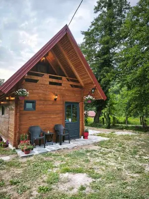 a log cabin with two chairs and a table at Janjske Otoke Brvnara Tiho Ognjiste in Šipovo
