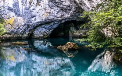 a cave in a river with blue water at Apartman ARIS in Bosanska Krupa