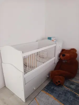 a brown teddy bear sitting next to a crib at Apartman ARIS in Bosanska Krupa