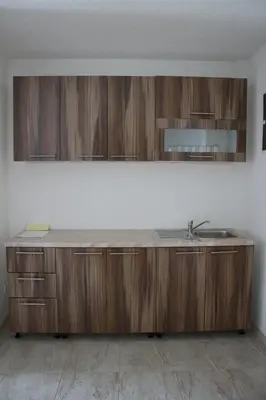 a kitchen with a sink and wooden cabinets at Villa Leamax - Stan 9 in Velika Kladuša